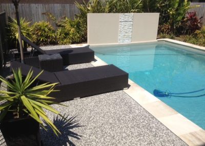 Exposed aggregate pool paving with natural stone coping