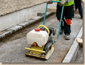 Using a wacker to compress the road base prior to paving